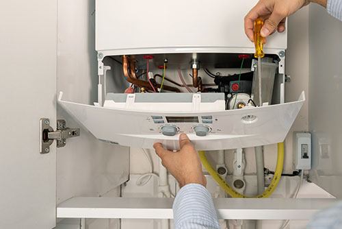 Heating technician repairing a residential boiler in Oakdale