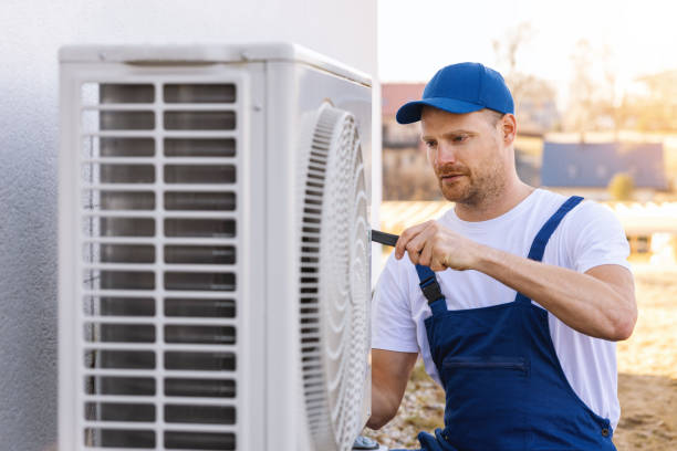 HVAC technician servicing an outdoor air conditioner in Oakdale