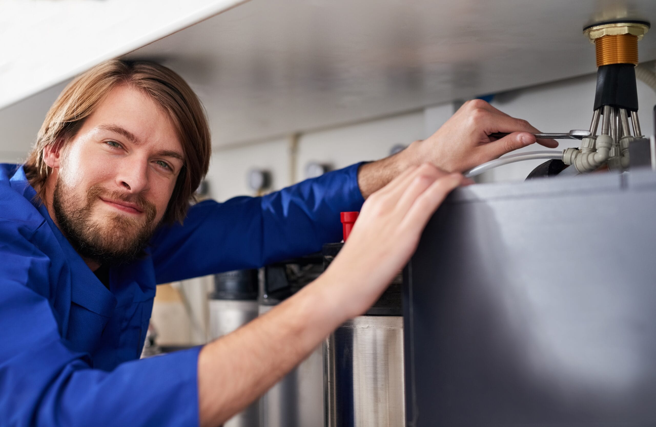 Technician servicing a residential water heater tank in Oakdale